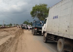 ２台のトラックが道をふさぎ、通行止め。右側に流れる小運河を渡り迂回することに