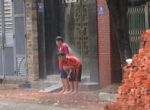 屋根から流れる雨水で遊ぶ兄弟